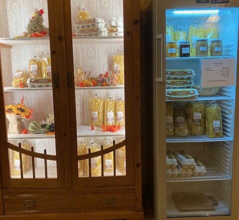 Holzschrank und Kühlschrank mit hausgemachten Produkten wie Nudeln, Eiern und Marmelade